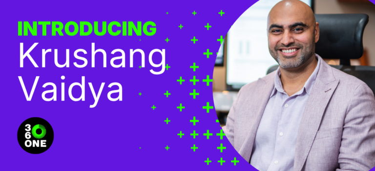 Image of Krushang Vaidya wearing a light grey suit jacket with an office in the background that is blurred out. The image is set in a banner with a purple background that says Introducing Krushang Vaidya